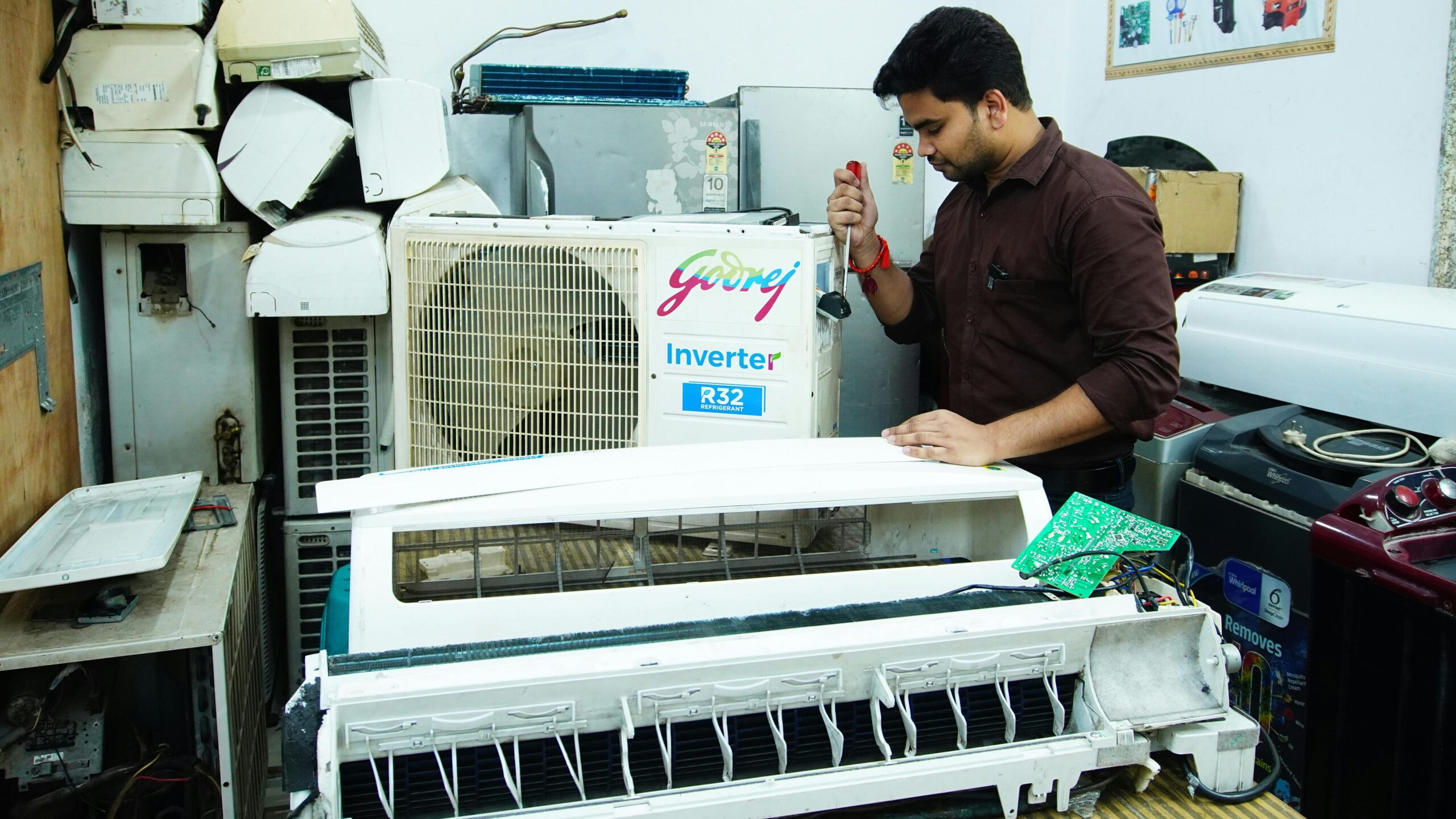 Technician repairing an air conditioner unit in New Delhi workshop.